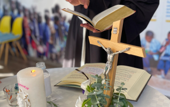 Image of a priest reading a passage from the bible.