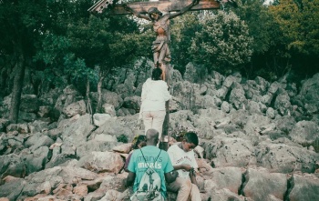 children with father praying on Apparition Hill in front of Cross