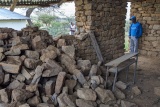 Image of a Mary's Meals employee standing next to a collapsed wall.