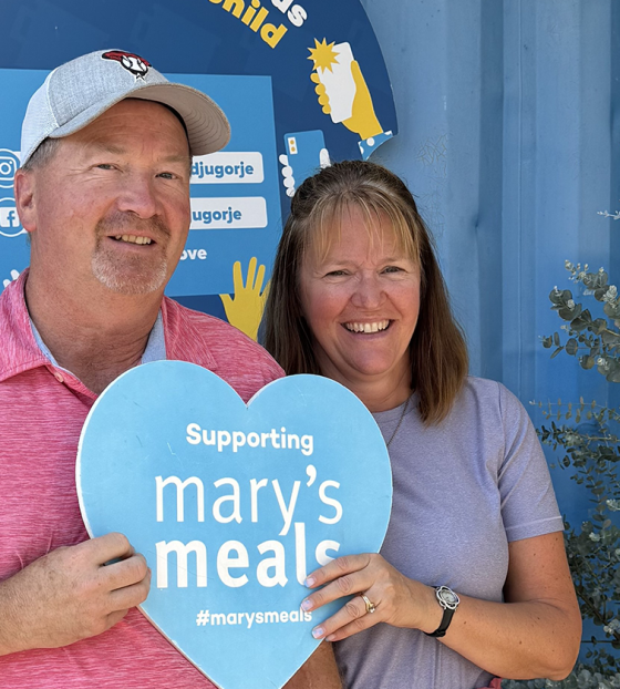 Emely and Shane holding up a love heart Mary's Meals sign. 