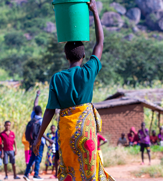 Image of woman carrying a large jug on her head.