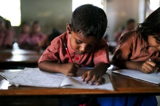 A child writes in a notepad in a classroom.