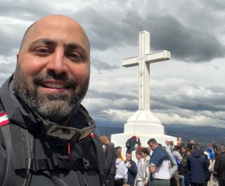 A man in front of Cross statue on Cross Mountain
